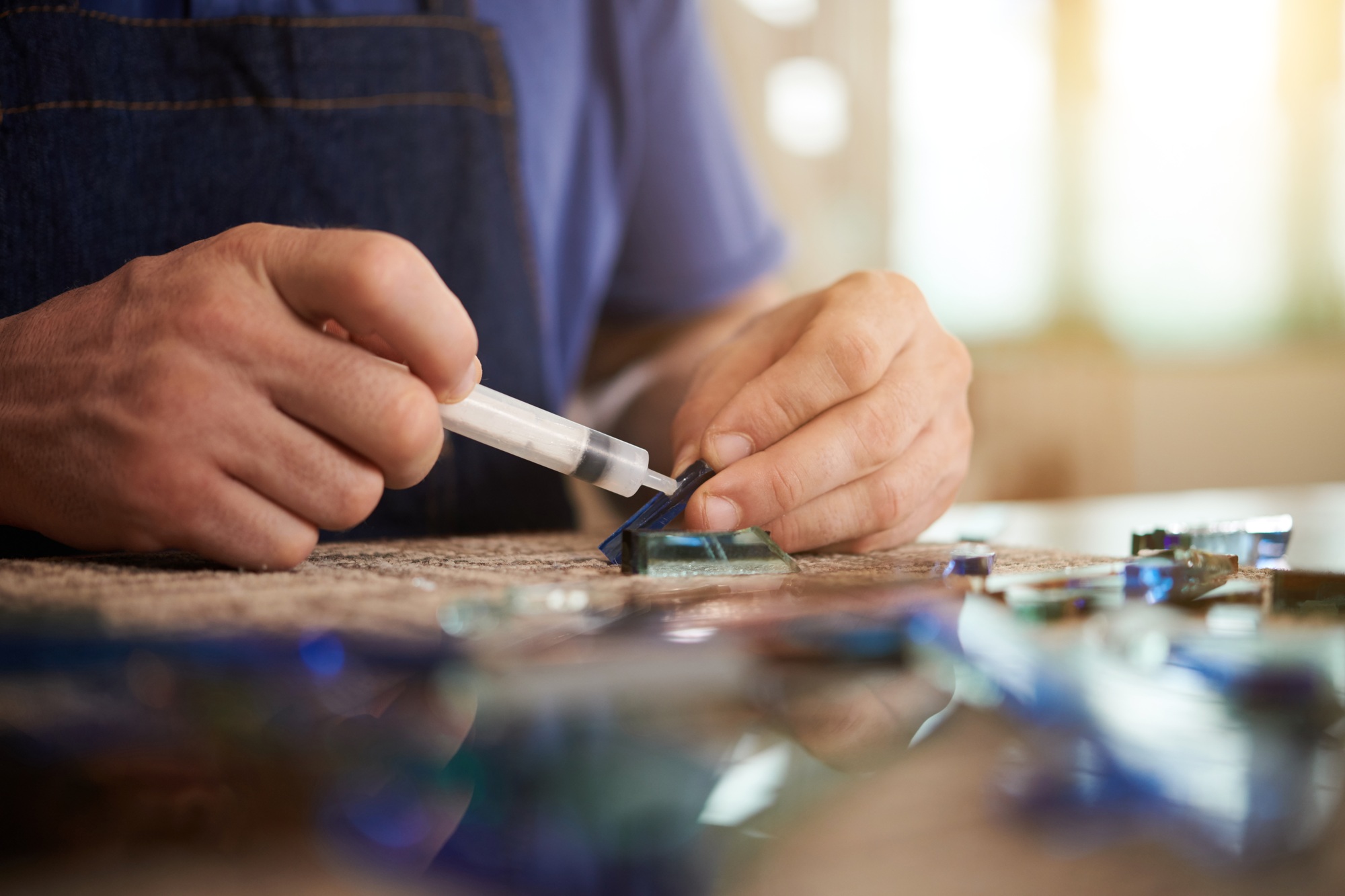 Worker using glue to make craft from glass